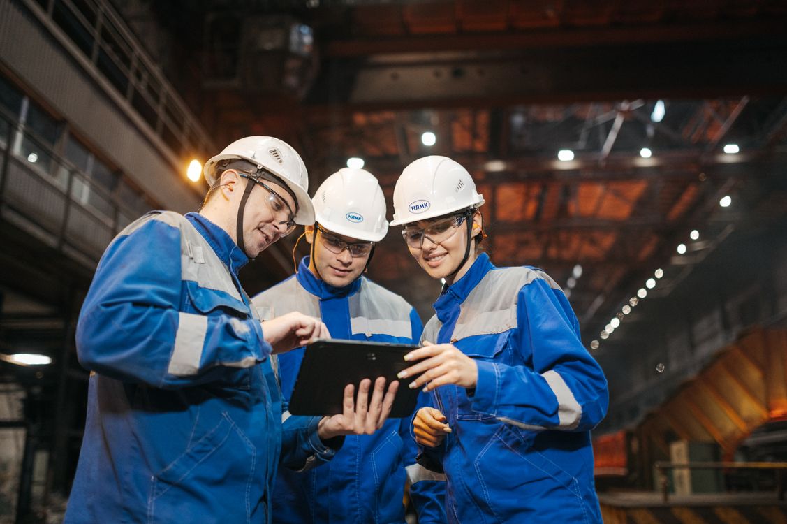 An operations team reviewing a tablet together on a factory floor